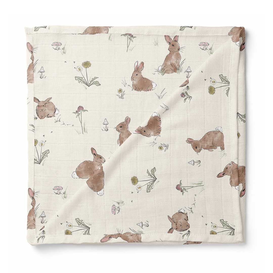 A square muslin baby blanket with a printed pattern of brown rabbits and small wildflowers on an off-white background, shown flat against a white background.