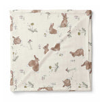 A square muslin baby blanket with a printed pattern of brown rabbits and small wildflowers on an off-white background, shown flat against a white background.