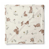 A square muslin baby blanket with a printed pattern of brown rabbits and small wildflowers on an off-white background, shown flat against a white background.