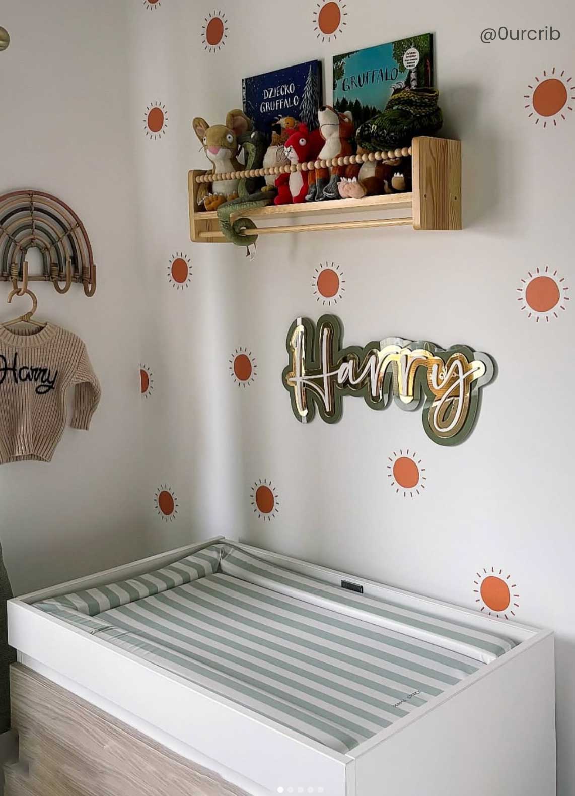 Baby's nursery with a crib, wall decorations, and a sage green changing mat