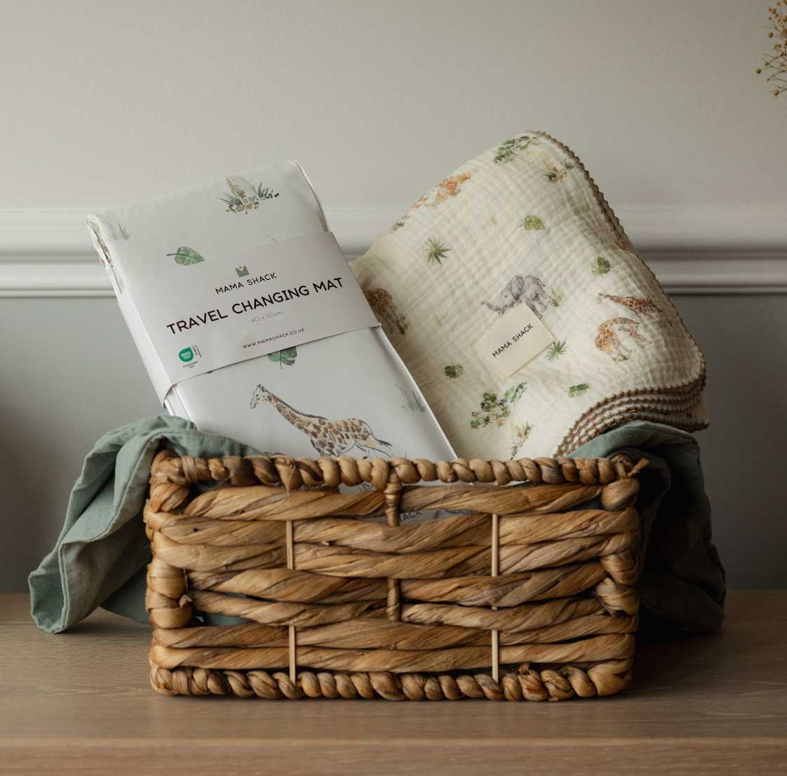 Woven basket with baby changing mat and blanket on a wooden surface