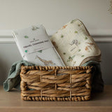Woven basket with baby changing mat and blanket on a wooden surface