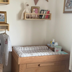 Nursery room with wooden changing table, shelves, and decorative elements.