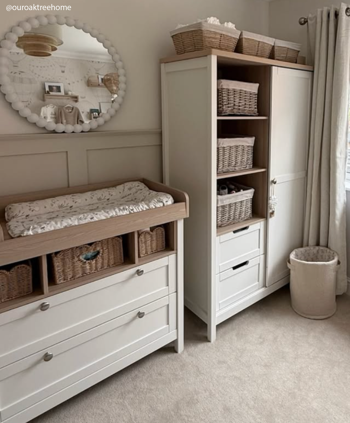 Nursery room with white changing table and storage unit, featuring baskets and a mirror.