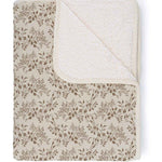 Floral patterned blanket with textured border on a white background