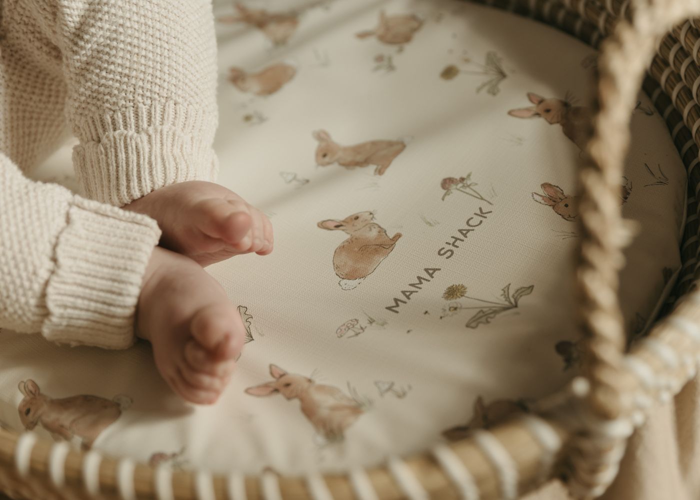 close up of mama shack changing mat in a moses basket with baby feet