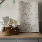 Baby changing table with a basket of items and a sheet with animal pattern on a wooden surface.