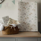 Baby changing table with a basket of items and a sheet with animal pattern on a wooden surface.